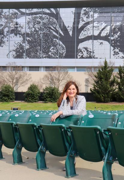 Kerry Painter sitting in the Red Hat Amphitheater with the Atlantic Union Bank Convention Center shimmer wall in the background
