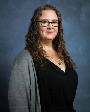 Headshot of Kris Wyatt wearing glasses, a black top, and gray cardigan.